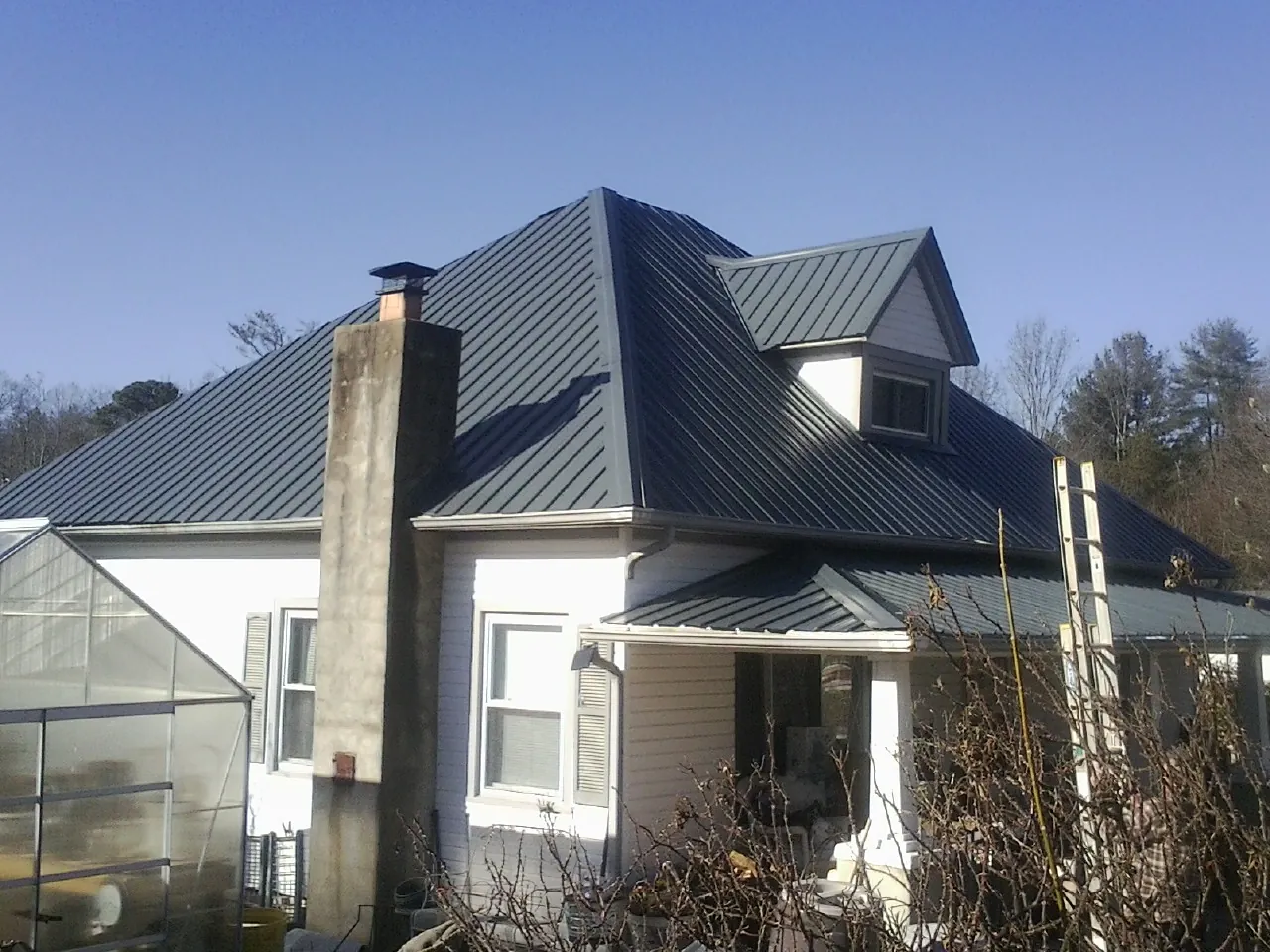Dark blue standing seam metal roof on a white farmhouse with dormer — Slate & Tile Roof Repair by Roofing Brothers in Coquille