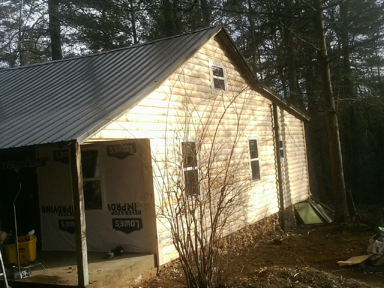 Log siding gable end under a dark metal roof edge in Coquille