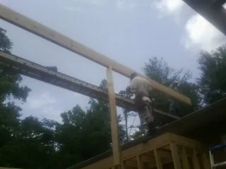 Carpenter setting a ridge beam over a new addition frame — Ice Dam Removal by Roofing Brothers in Coquille