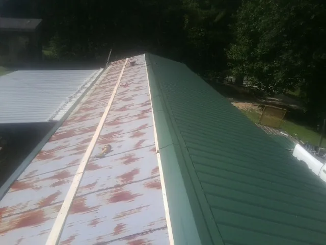 Old rusted panels beside newly installed green metal roofing — Wind Damage Roof Repair by Roofing Brothers in Coquille