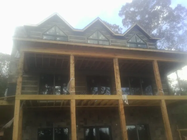 Dormers and porch framing on a large log home under construction — Roof Coating work by our crew in Coquille