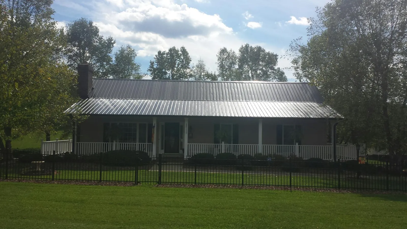 Gray metal roof on a brick ranch with a full width front porch — Gutter Guard Installation work by our crew in Coquille