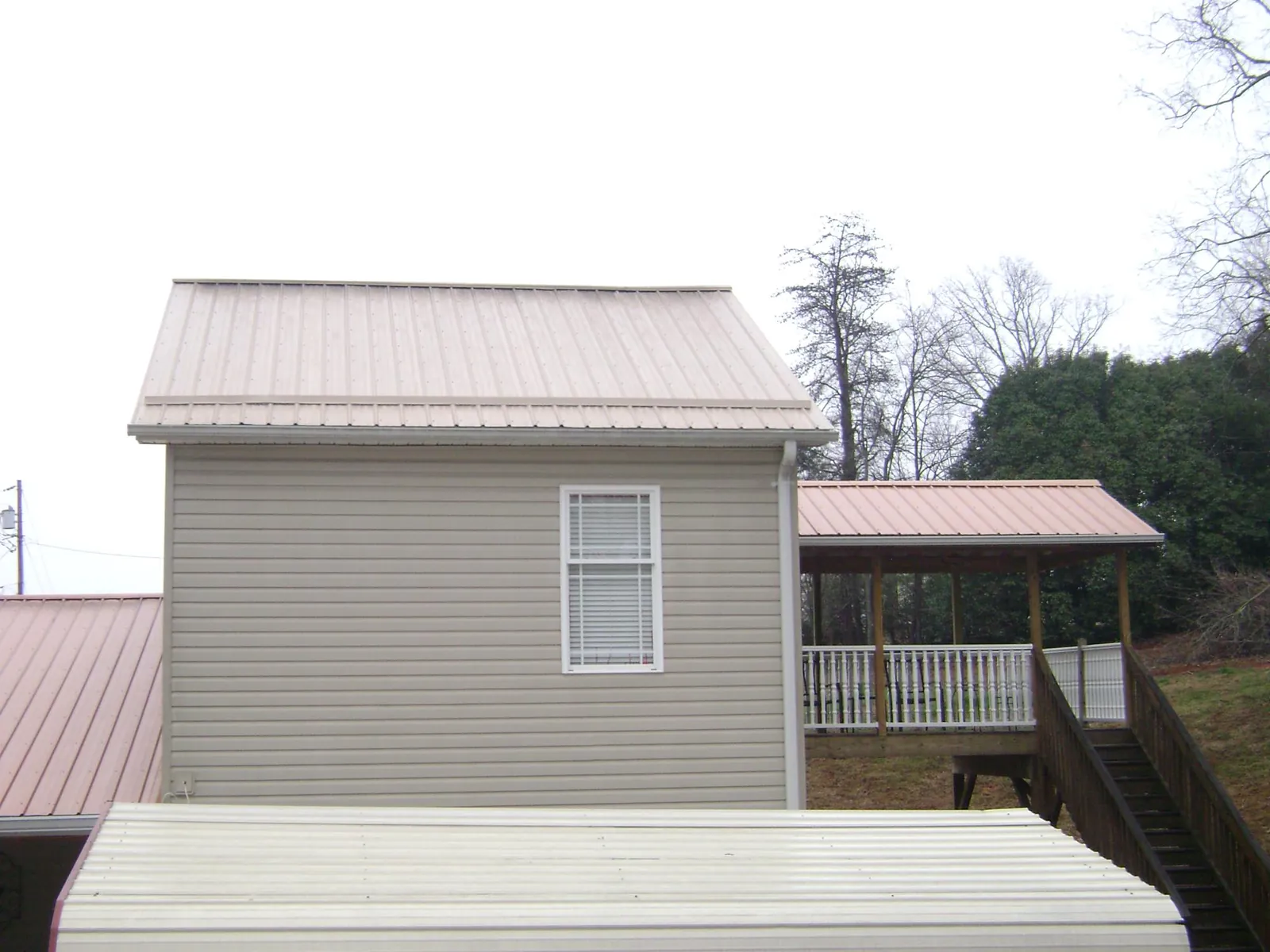 Tan metal roofs on a two story addition and attached porch, from a Roof Replacement job in Coquille