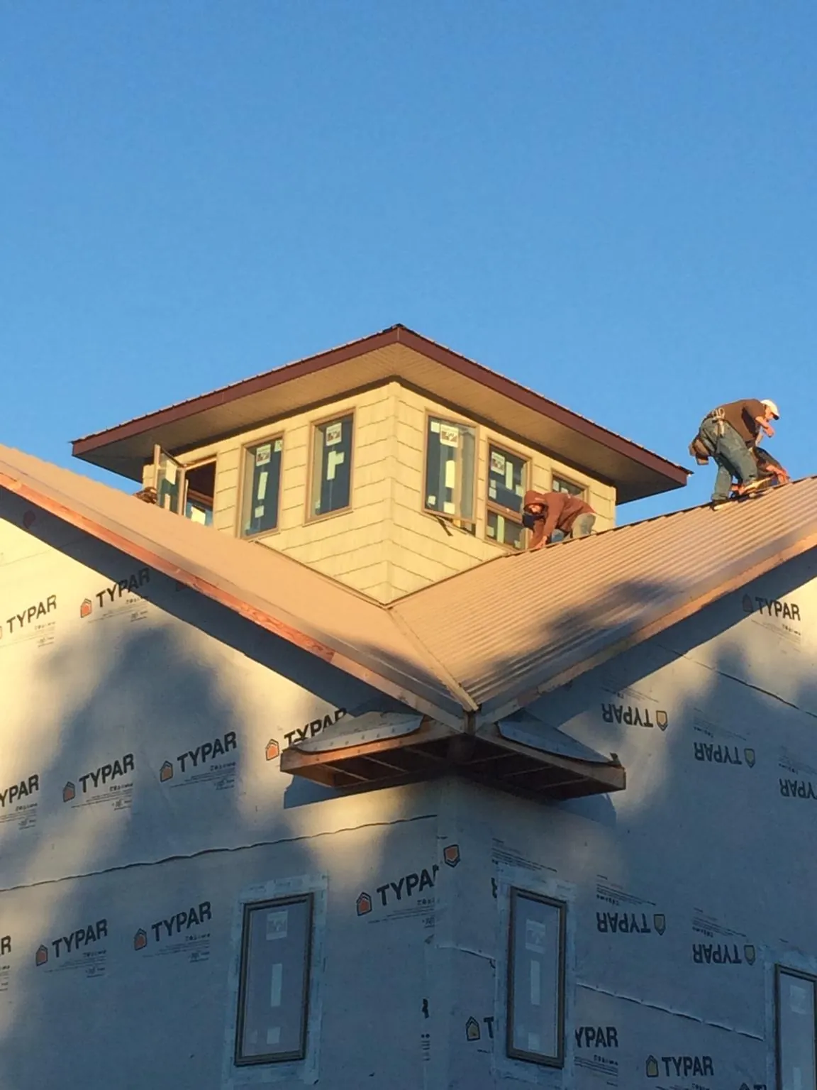 Roofers working around a rooftop cupola on a new metal roof at sunset — Roof Waterproofing in Coquille by Roofing Brothers